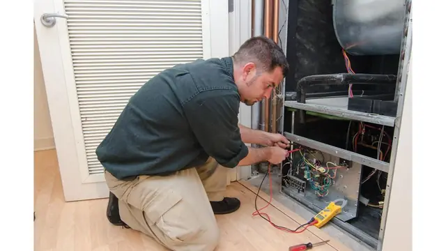 Technician at an open indoor air handler with meter leads on the control board