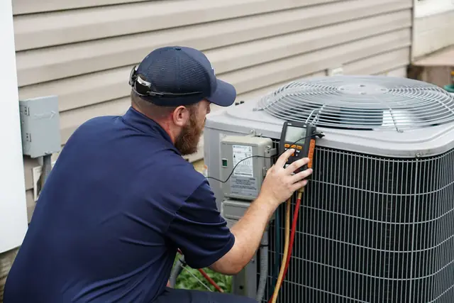 Technician at an outdoor condenser with a digital meter and copper line set