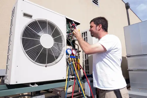 Technician at a condenser with a full manifold gauge set connected