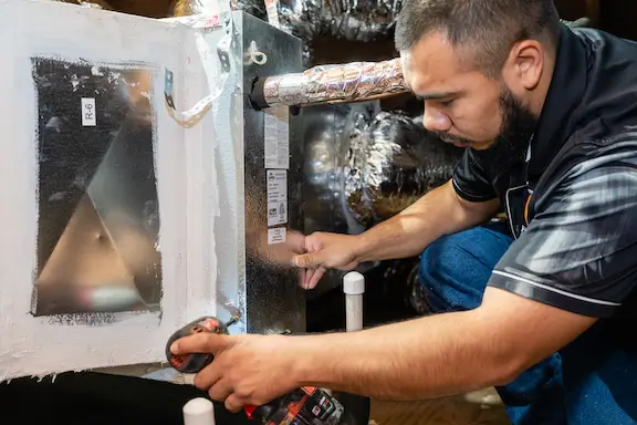 Prestige technician working on an indoor air handler and ductwork